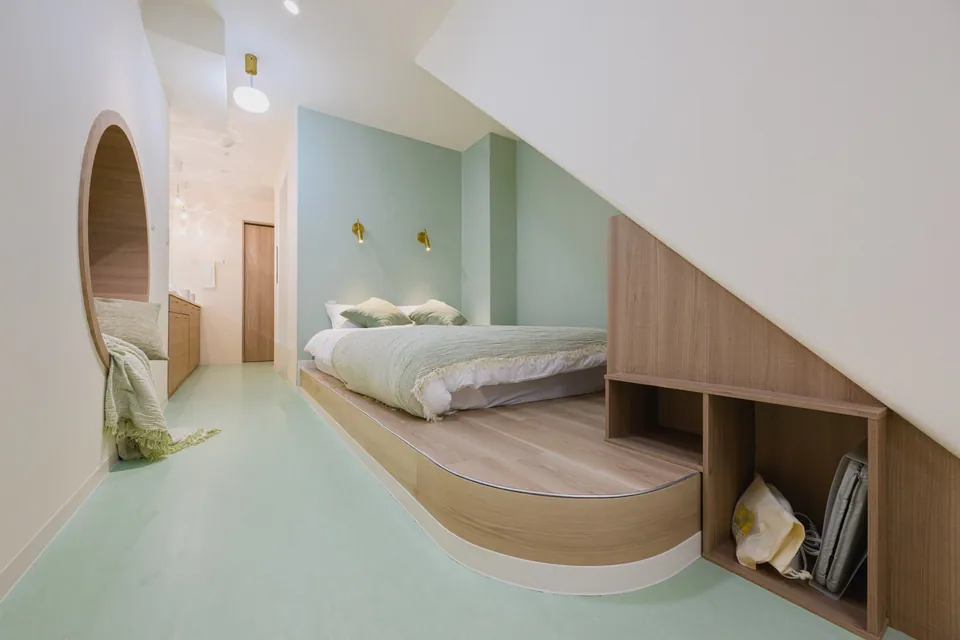The wooden bed and mint green sleeping area at ARiA STAY HATSUDAI