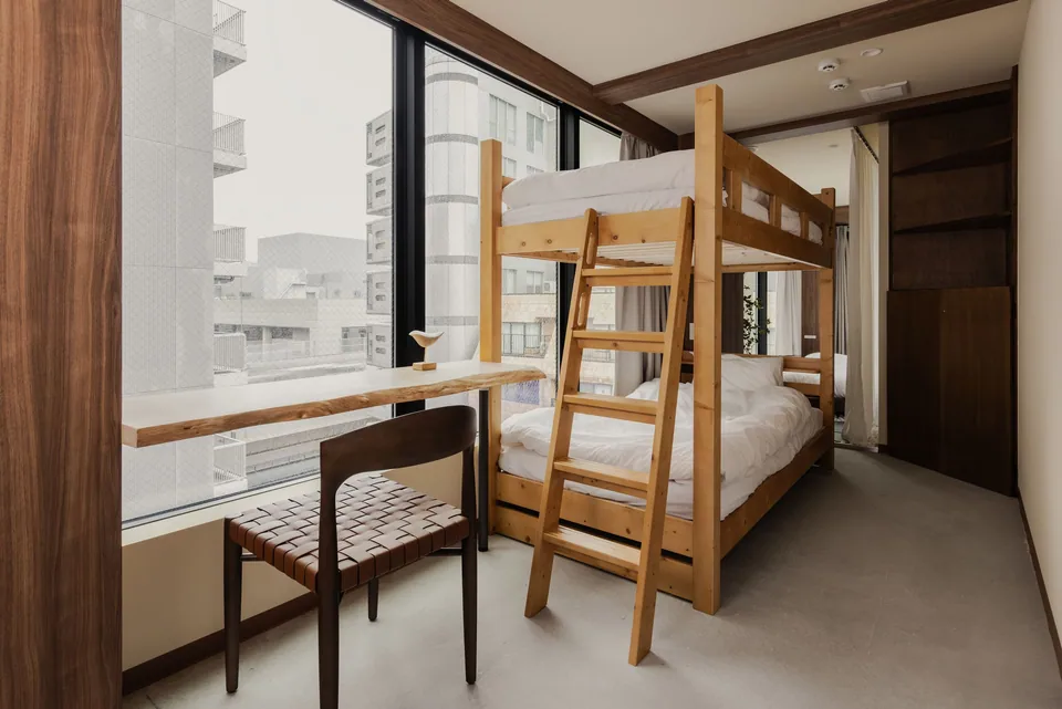 The wooden bunk bed and desk beside the window at Komorebi Stay