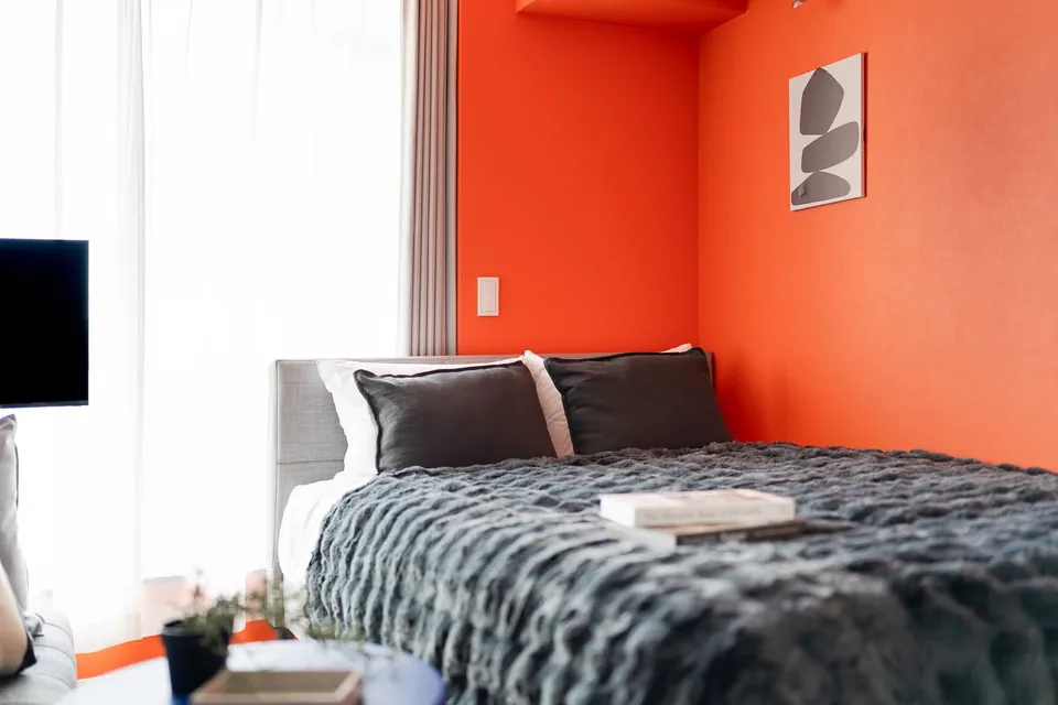 The bed against an orange wall in SB3A