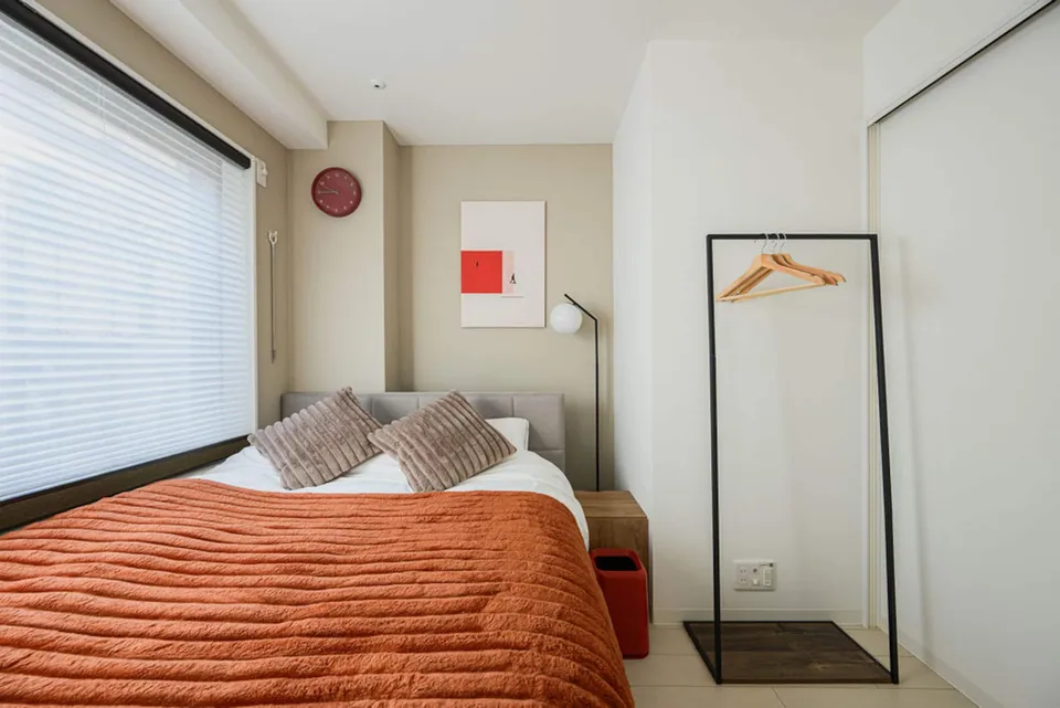 A bedroom in Takanawa 101, with a red bedspread beside the window
