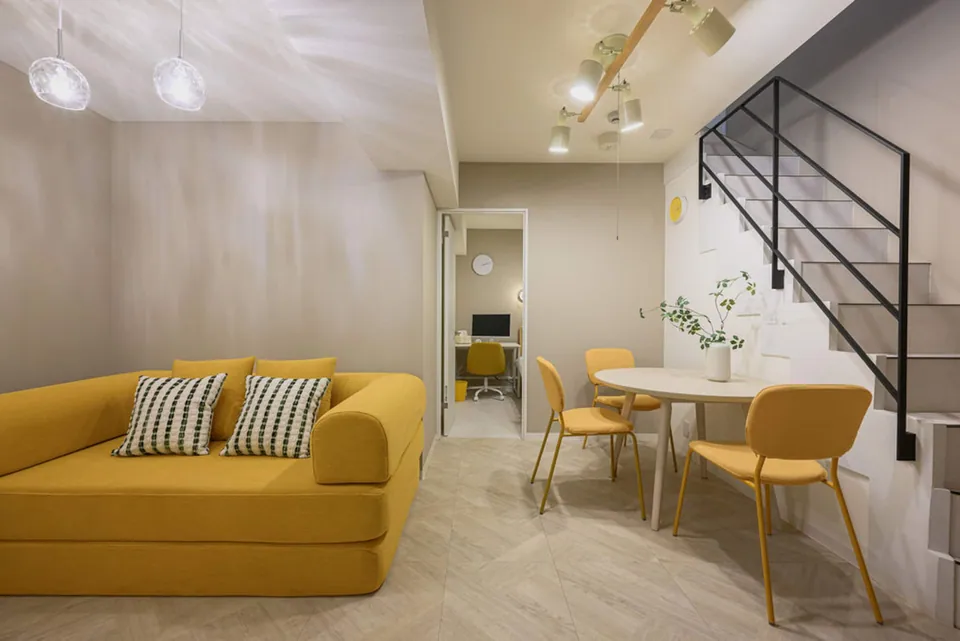 The yellow sofa, dining area and black stair railing in Takanawa 102