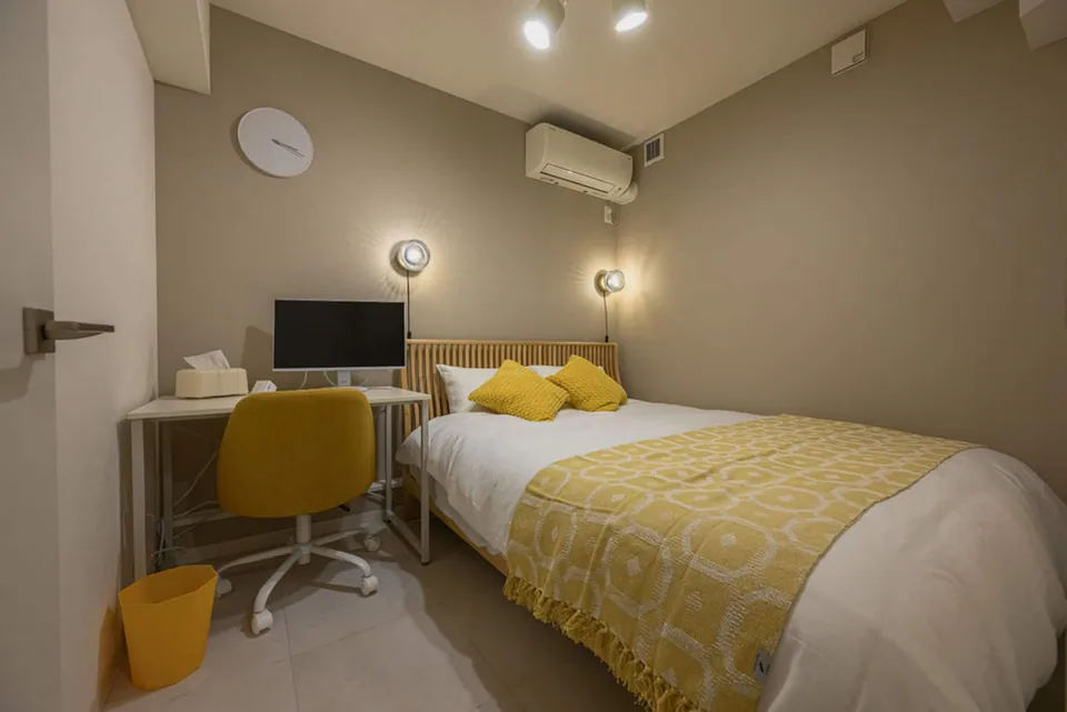 The second bedroom in Takanawa 102, with a desk and yellow chair