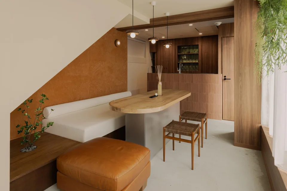The dining area at Komorebi Stay in Hatsudai, with wood-panelled walls, a white built-in bench and an oval table.