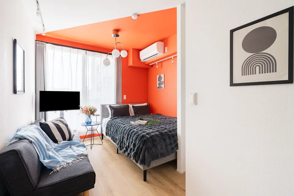 SB3A: Orange & grey. Bright orange walls, grey bedding and round lights bring a playful palette to a compact studio.