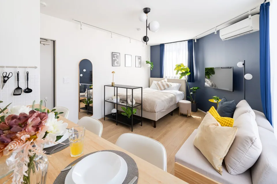 SB51: Navy & yellow. Deep blue walls, a white sofa and yellow accents, with sleeping space in the bedroom and living area.
